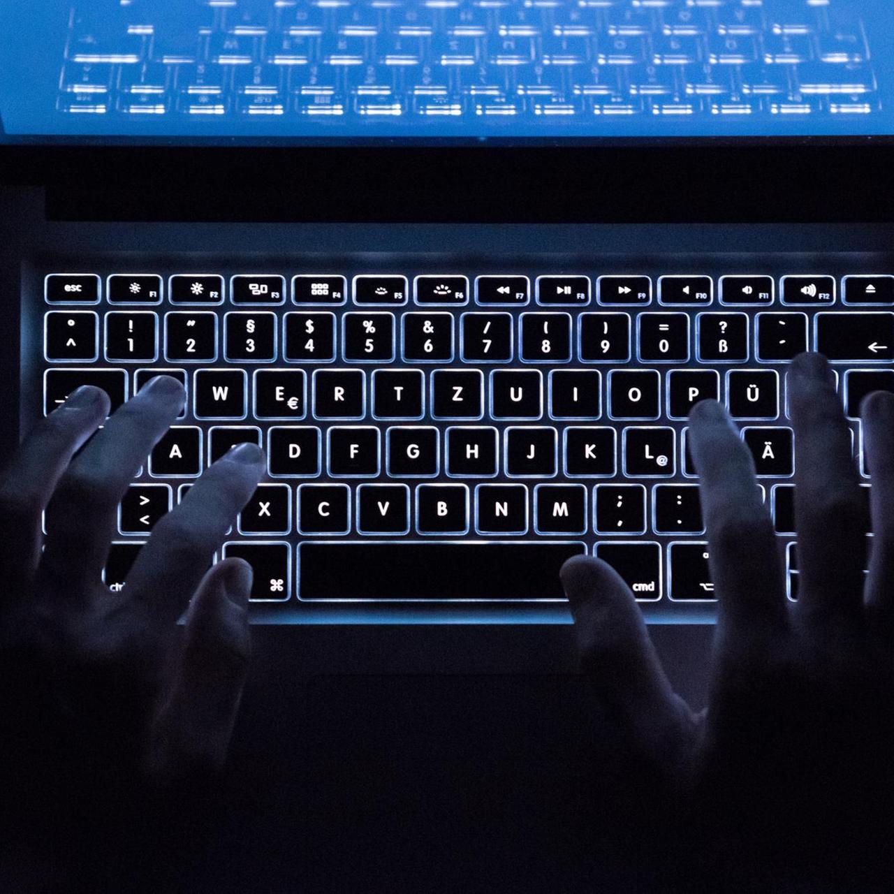 Hande über einer beleuchteten Computertastatur
