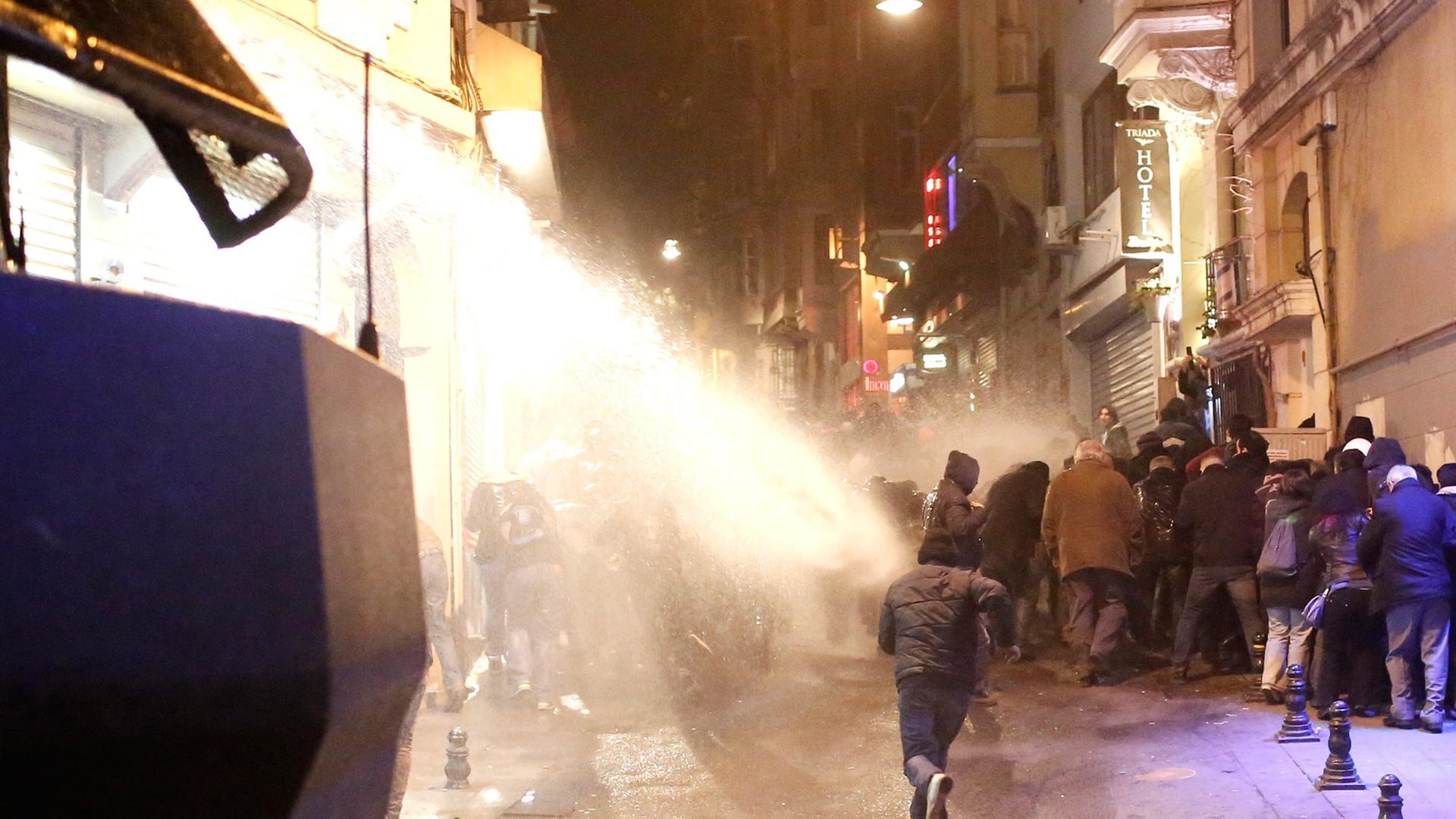 Demonstranten fliehen vor einem Wasserwerfer der Polizei.