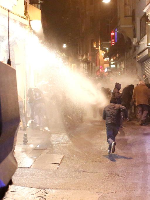 Demonstranten fliehen vor einem Wasserwerfer der Polizei.