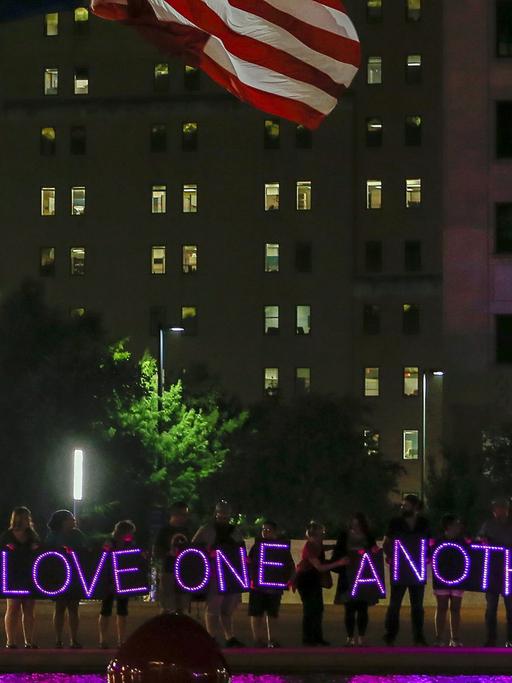 Menschen halten bei einer Nachtwache auf dem Platz vor der City Hall in Dallas LED-Lichter mit dem Schriftzug "Love one another" - liebt einander - hoch, aufgenommen am 11. Juli 2016.