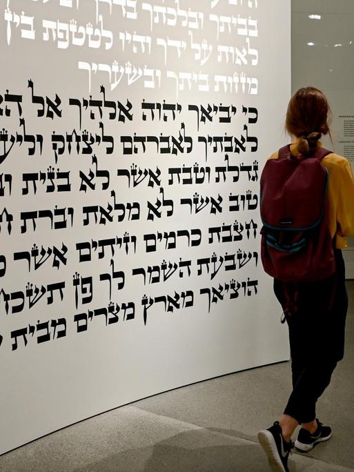 Eine junge Frau geht in der neuen Dauerausstellung «Jüdische Geschichte und Gegenwart in Deutschland» im Liebeskind-Bau des Jüdischen Museums durch den Themenraum «Tora».