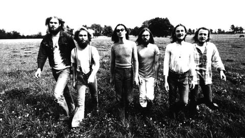 Das Schwarzweiß-Bild zeigt sechs Männer auf einem Feld. Sie tragen das Haar länger, zum Teil tragen sie Bart.