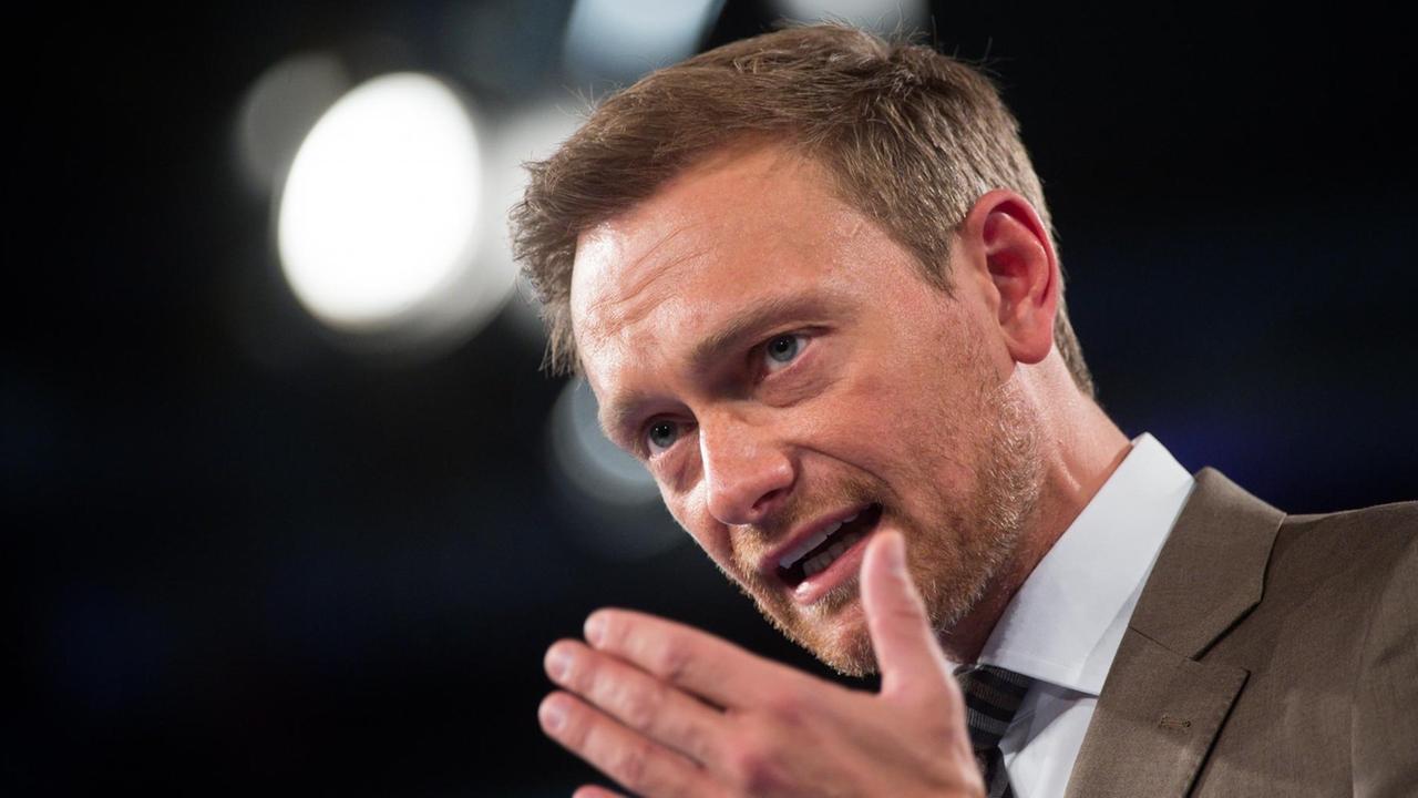 Lindner spricht und gestikuliert vor einem schwarzen Hintergrund.Hinter seinem Kopf leuchtet ein weißes Licht. Lindner spricht und gestikuliert vor einem schwarzen Hintergrund.Hinter seinem Kopf leuchtet ein weißes Licht.