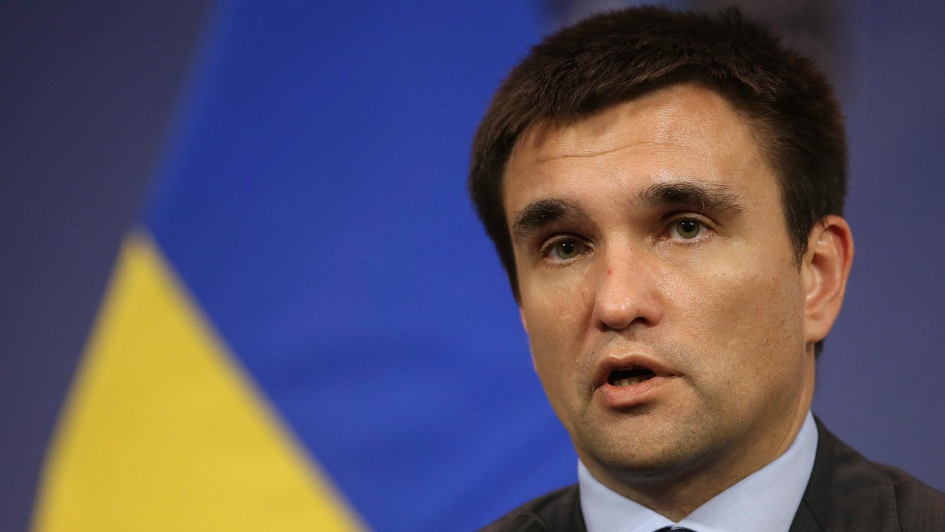 Der ukrainische Außenminster Pawel Klimkin, sprechend, eine gelb-blaue Fahne im Hintergrund.