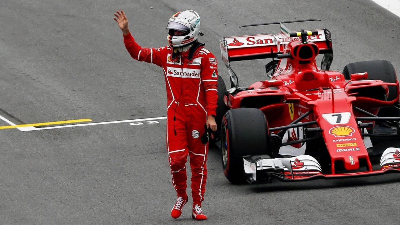 Der Renn-Fahrer Sebastian Vettel winkt.