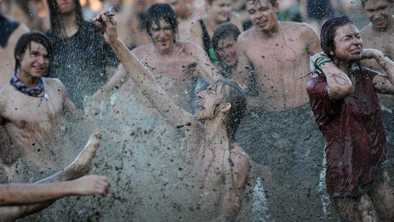Ein Festivalbesucher badet am 02.08.2013 beim Musikfestival "Haltestelle Woodstock" in der polnischen Stadt Kostrzyn (Küstrin) im Schlamm.