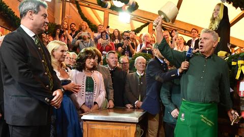 Markus Söder, Ministerpräsident von Bayern, und seine Frau Karin Baumüller-Söder schauen Dieter Reiter (SPD), Oberbürgermeister von München beim traditionellen Fassanstich zu.