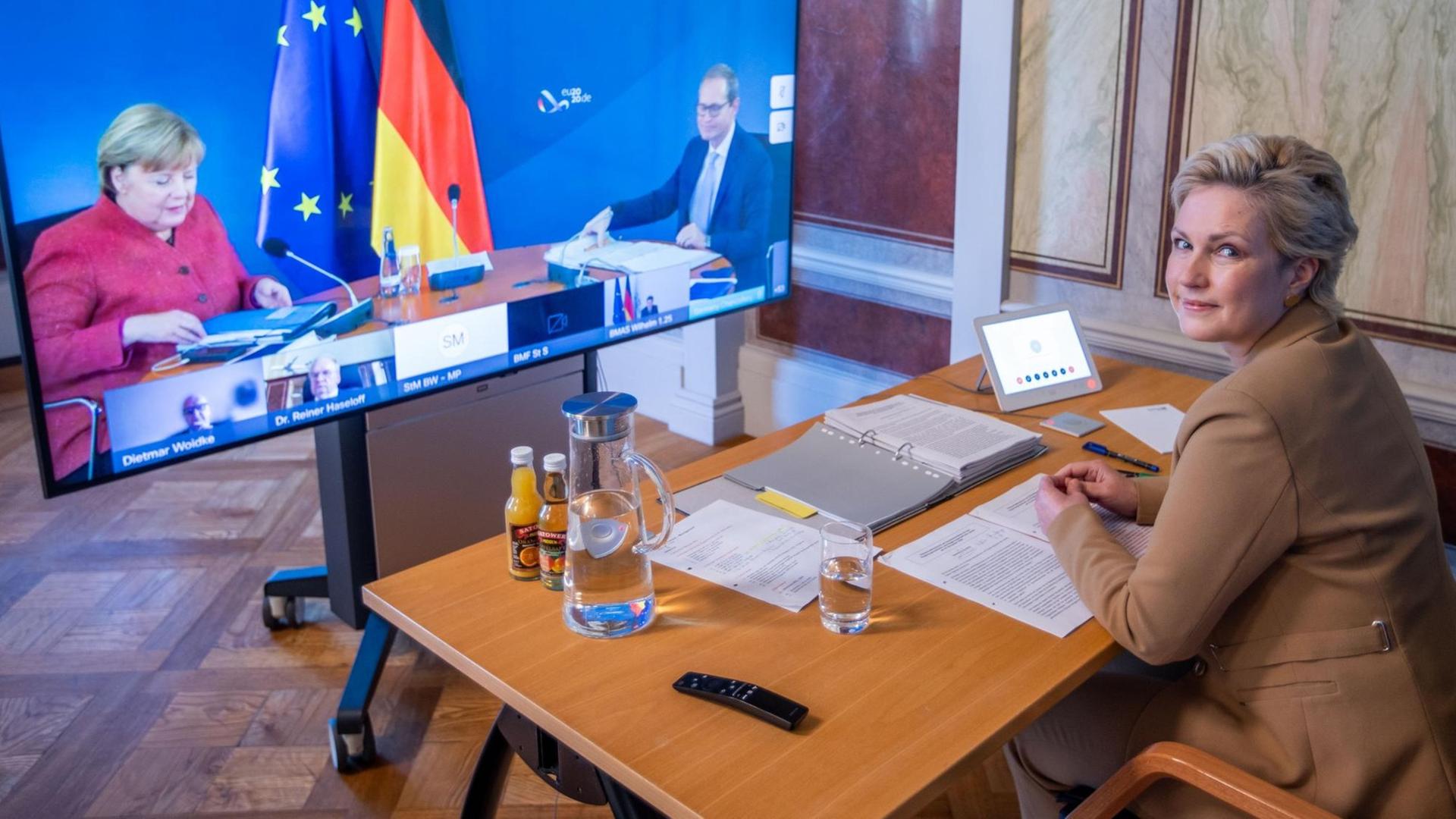 Manuela Schwesig (SPD), Ministerpräsidentin von Mecklenburg-Vorpommern, sitzt in der Staatskanzlei bei der Video-Schaltkonferenz zur Entwicklung der Corona-Pandemie vor einem Monitor auf dem Bundeskanzlerin Angela Merkel (CDU) und Michael Müller (SPD), der Regierende Bürgermeister von Berlin, zu sehen sind.