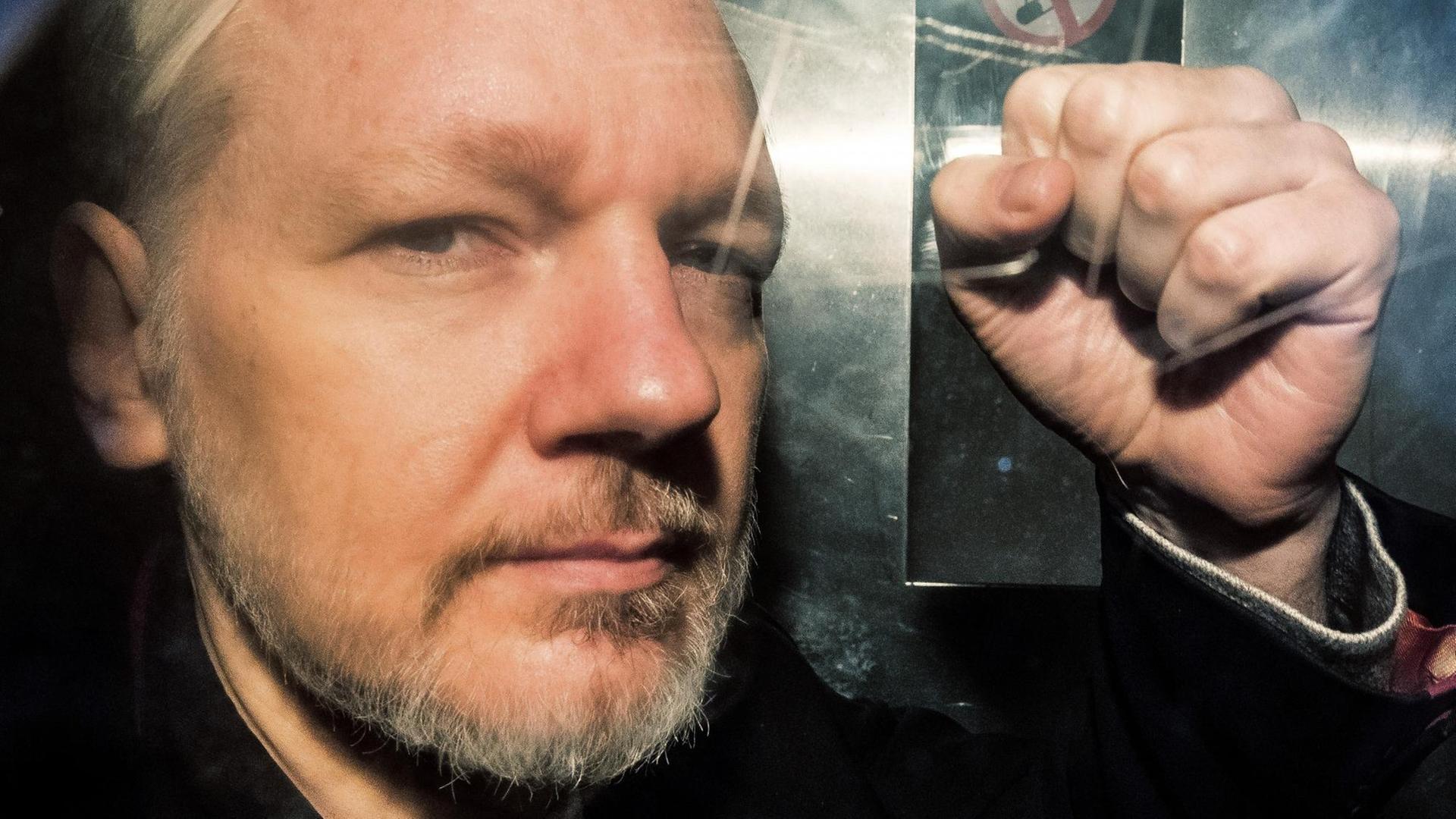 Julian Assange droht mit der Faust. 