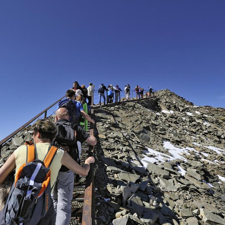 Viele Touristen laufen hintereinander zur Aussichtsplattform "Top of Tyrol" in den Stubauer Alpen hinauf

