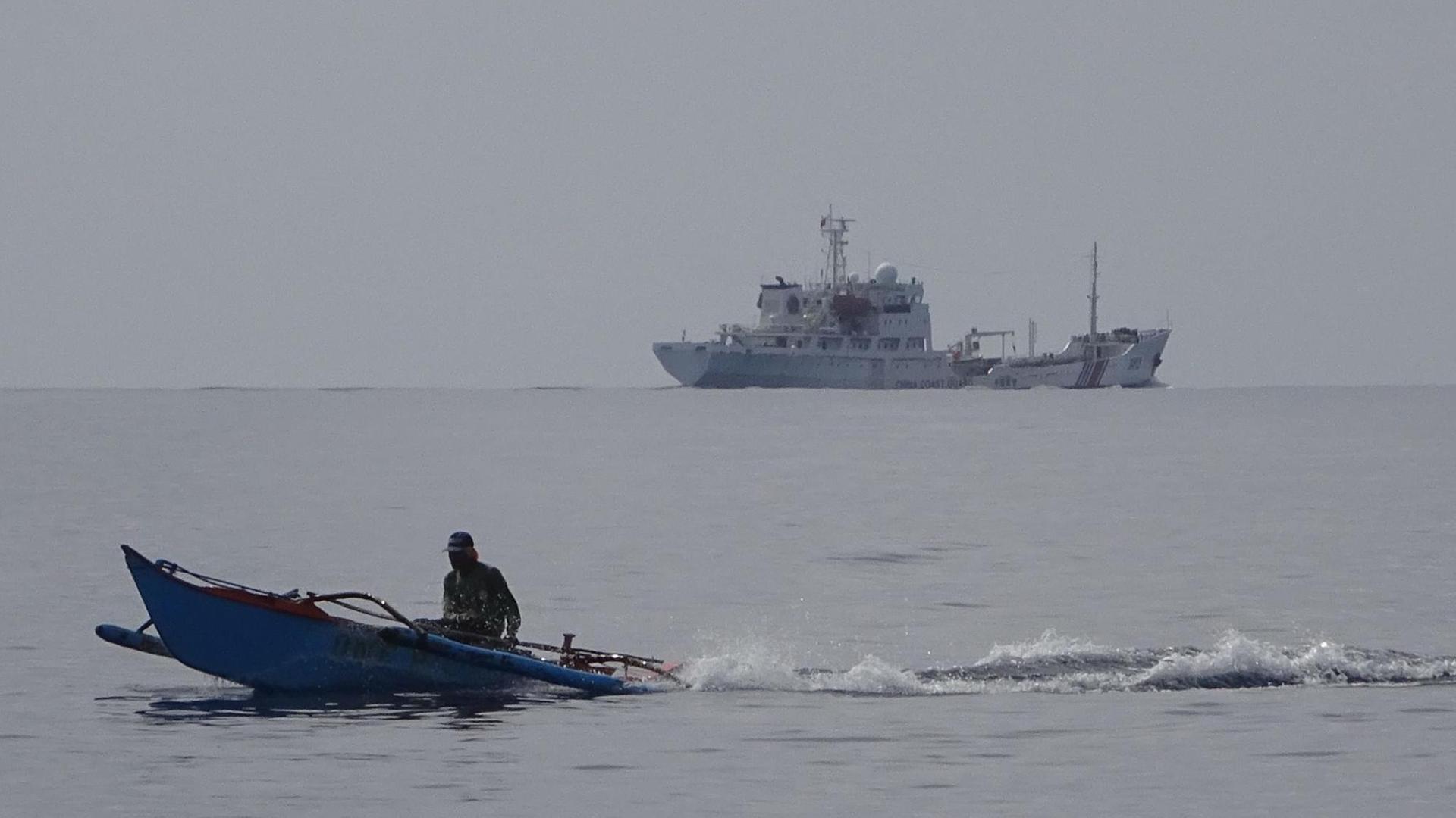 Ein philippinisches Fischerboot fährt vor einem chinesischen Militärboot