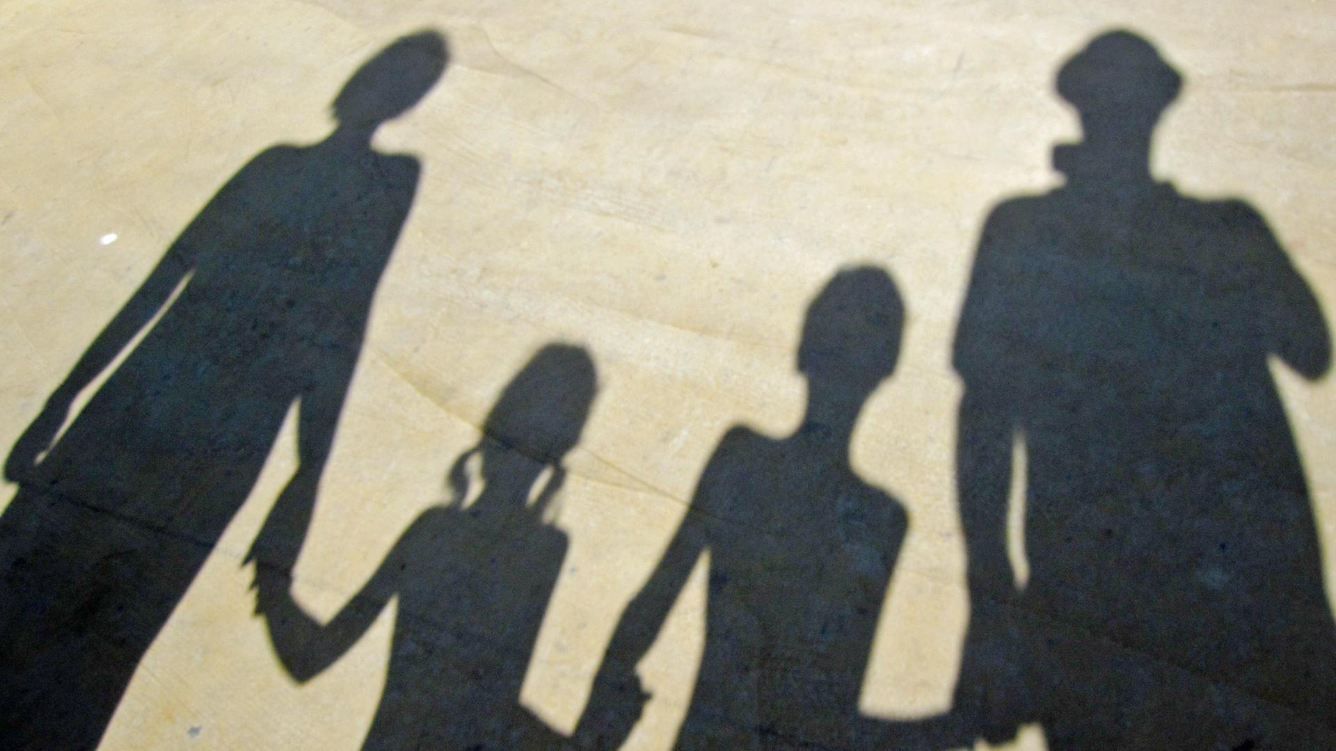 Der Schatten einer Familie, die sich an der Hand hält.