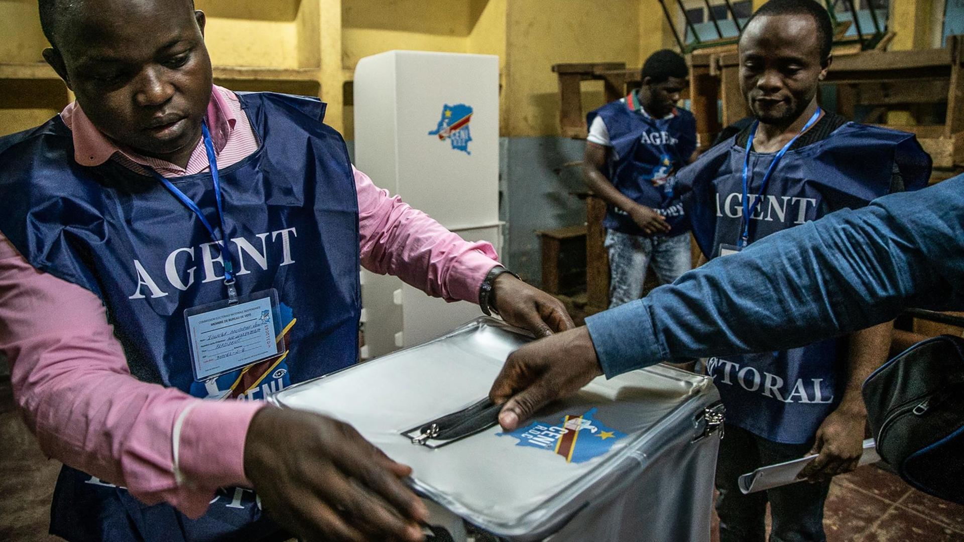 Das Foto zeigt Mitarbeiter der Wahlkommission an einer Urne für die Präsidentschaftswahl in der Demokratischen Republik Kongo. Das Foto zeigt Mitarbeiter der Wahlkommission an einer Urne für die Präsidentschaftswahl in der Demokratischen Republik Kongo.