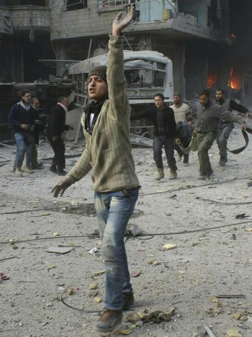 Ein von regierungskritischen Aktivistengruppe Ghouta Media Center zur Verfügung gestelltes und durch Abgleich mit AP-Berichterstattung authentifiziertes Bild zeigt Syrer, die ein Opfer des Angriffs durch die syrische Luftwaffe tragen (21.2.2018).