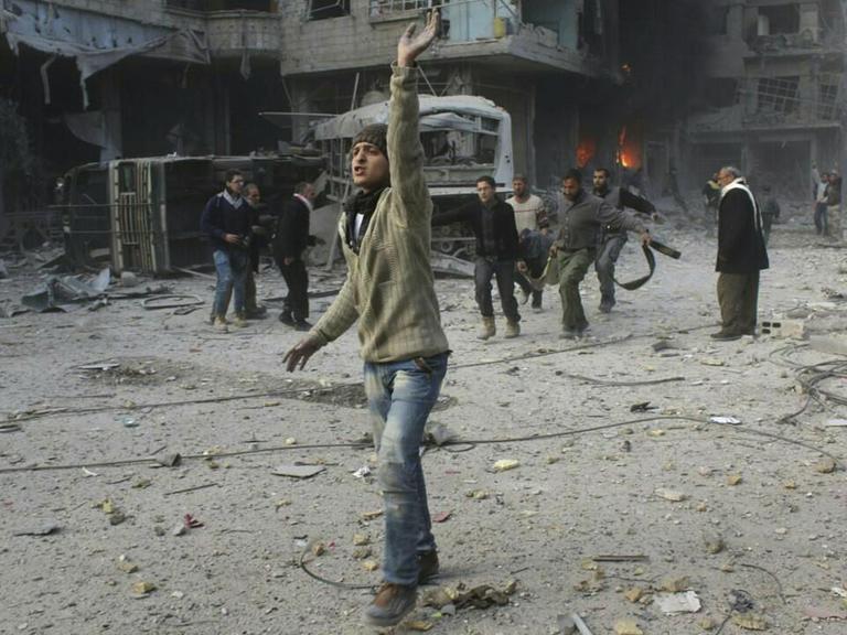 Ein von regierungskritischen Aktivistengruppe Ghouta Media Center zur Verfügung gestelltes und durch Abgleich mit AP-Berichterstattung authentifiziertes Bild zeigt Syrer, die ein Opfer des Angriffs durch die syrische Luftwaffe tragen (21.2.2018).