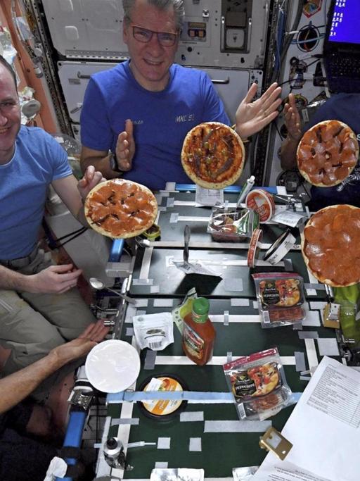 Das NASA-Bild zeigt die Astronauten Marke Vande Hei aus den USA (l-r), Sergei Rjasanski aus Russland, Paolo Nespoli aus Italien, Joe Acaba aus den USA und Randy Bresnik aus den USA, die auf der Internationalen Raumstation (ISS) ihre selbstgemachten Pizzen zeigen.
