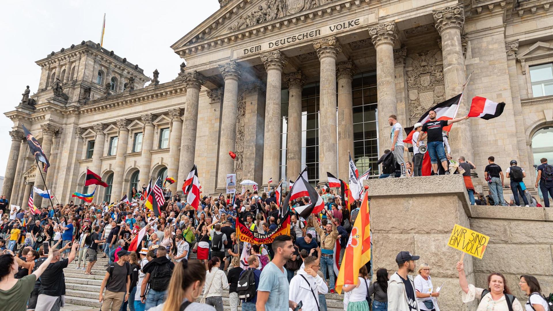 Teilnehmer einer Kundgebung gegen die Corona-Maßnahmen stehen auf den Stufen zum Reichstagsgebäude, zahlreiche Reichsflaggen sind zu sehen.