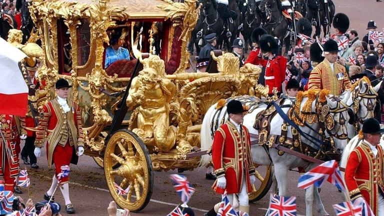 Zahlreiche Schaulustige winken der britischen Königin Elizabeth II. zu, die am 4.6.2002 mit der goldenen Kutsche durch London fährt.