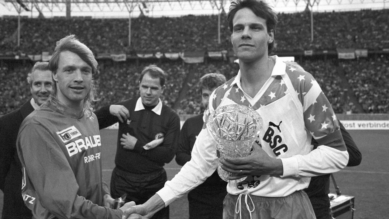 Die beiden Mannschaftskapitäne geben sich vor Beginn des innerstädtischen "Fußball-Gipfels" zwischen Hertha BSC und Union Berlin am 27.01.1990 im Olympiastadion in Berlin die Hand.