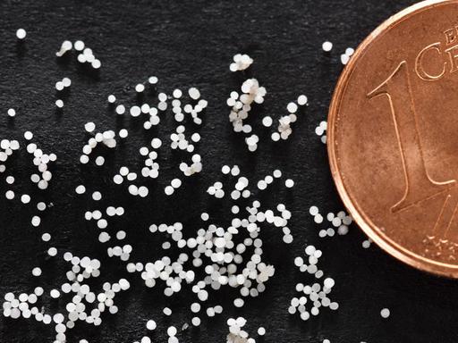 Mikroplastik-Partikel im Größenvergleich neben einer Ein-Cent-Münze