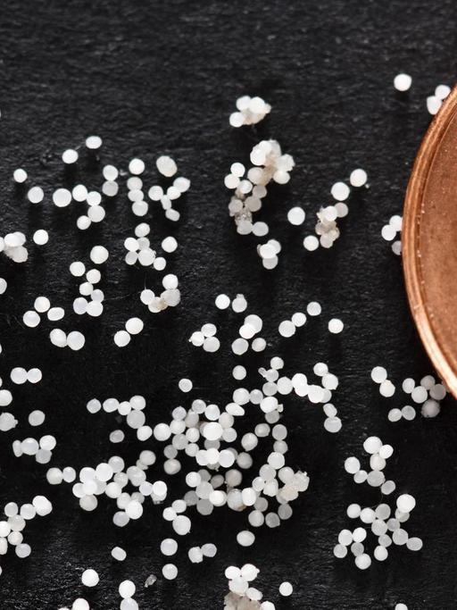 Mikroplastik-Partikel im Größenvergleich neben einer Ein-Cent-Münze