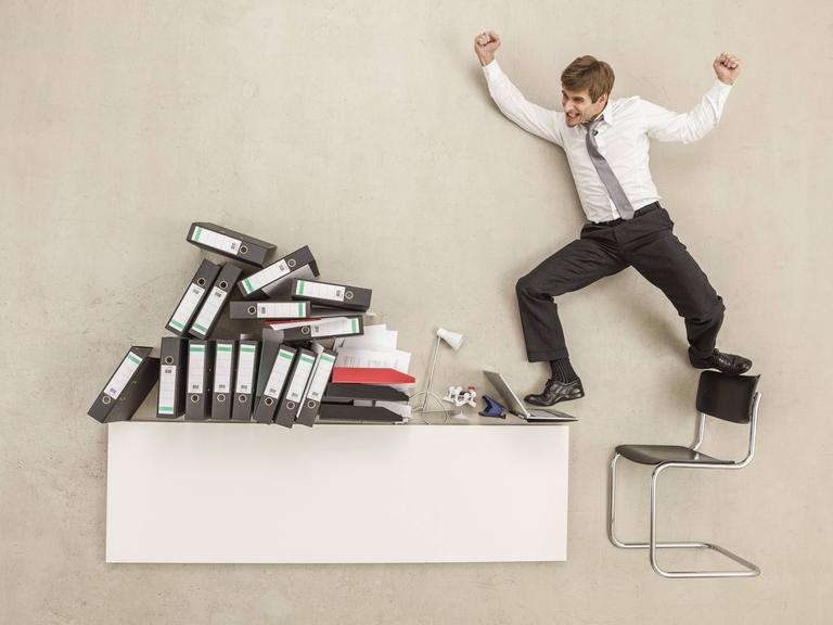 Ein Mensch springt auf seinen Bürostuhl und Tisch