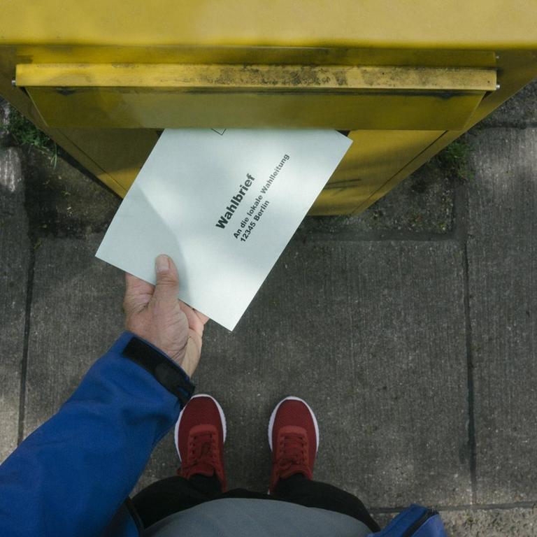 Eine Person wirft einem Wahlbrief in einen Briefkasten