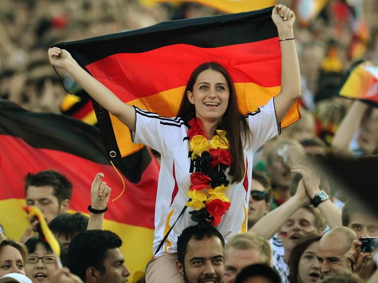 Deutsche Fußball-Fans schwenken auf der Fanmeile vor dem Brandenburger Tor Deutschlandfahnen