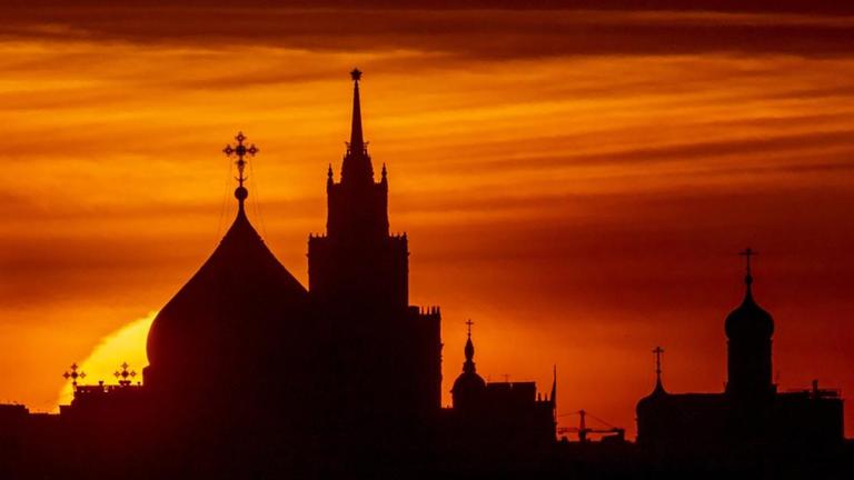 Hinter den Kuppeln einer Kirche in Moskau geht die Sonne unter.