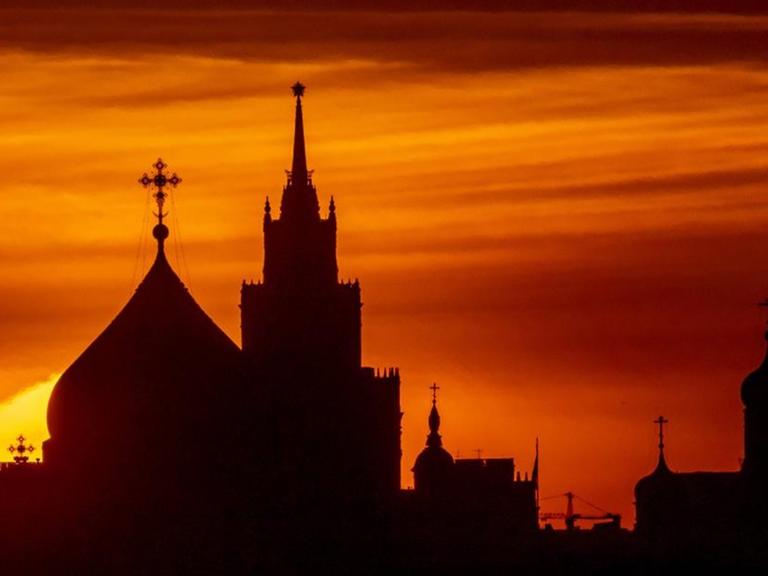 Hinter den Kuppeln einer Kirche in Moskau geht die Sonne unter.