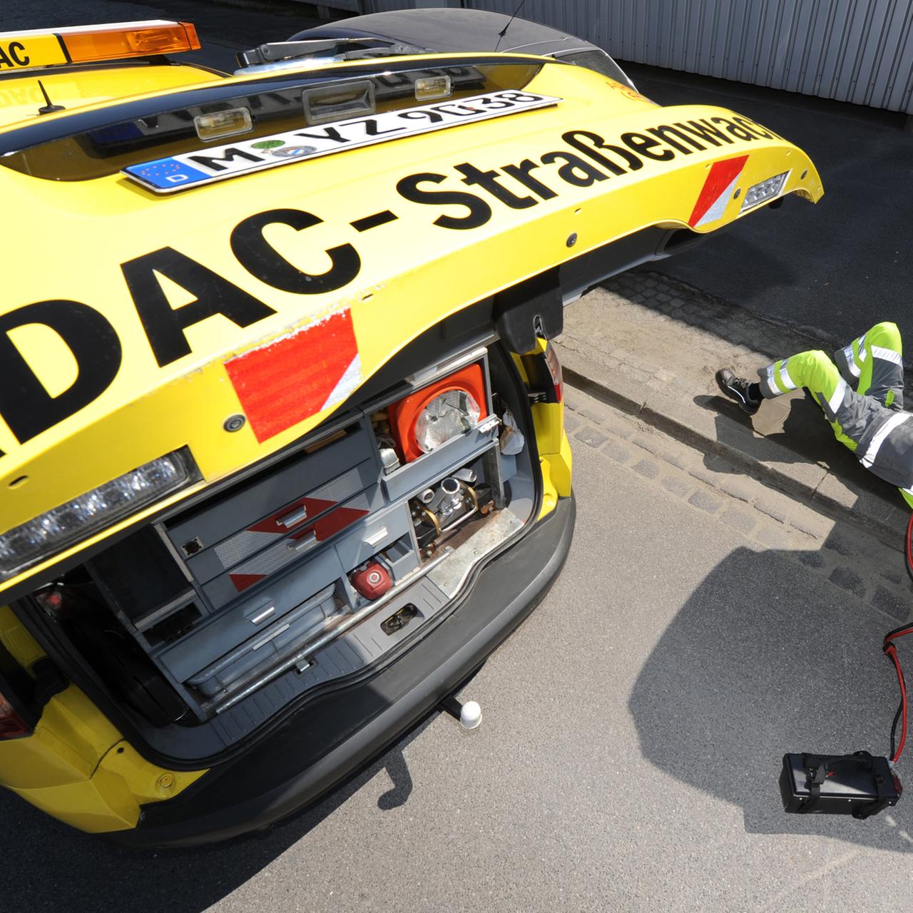 Ein ADAC-Mitarbeiter liegt unter einem Fahrzeug, links im Bild sein ADAC-Pannenhilfewagen