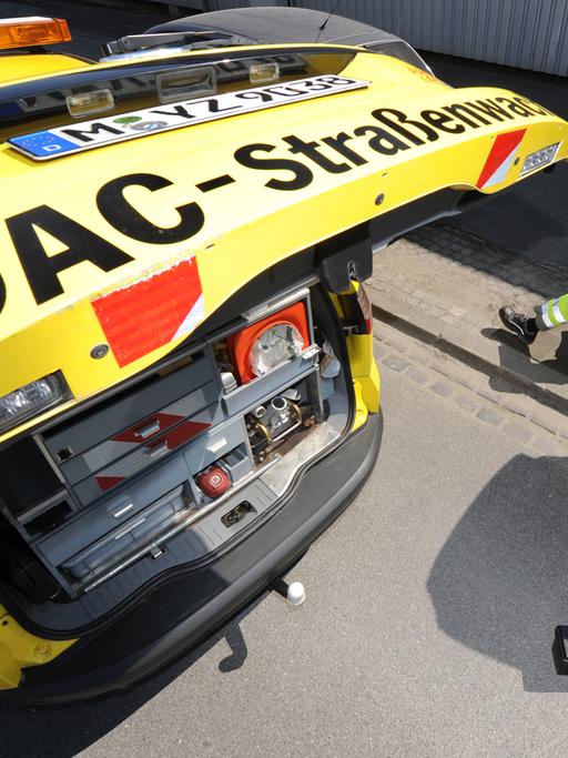 Ein ADAC-Mitarbeiter liegt unter einem Fahrzeug, links im Bild sein ADAC-Pannenhilfewagen