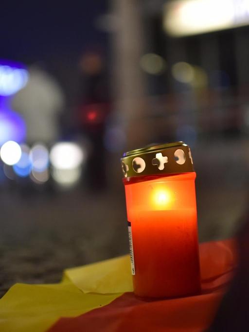 Ein Grablicht steht auf einer deutschen Fahne zum Gedenken an die Opfer vor dem Weihnachtsmarkt an der Gedächtniskirche in Berlin.