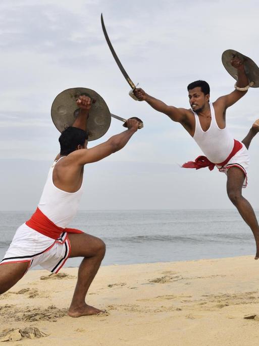 Zwei Kalaripayattu Kämpfer mit langen Säbeln und runden Schildern in Aktion