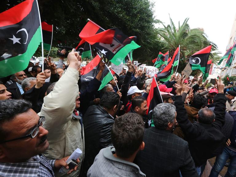 Menschen schwenken libysche Flaggen auf der Straße