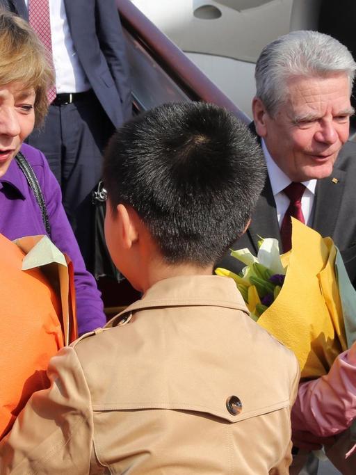 Bundespräsident Joachim Gauck und seine Lebensgefährtin Daniela Schadt werden auf dem Flughafen von Peking in China von Kindern mit Blumen begrüßt.