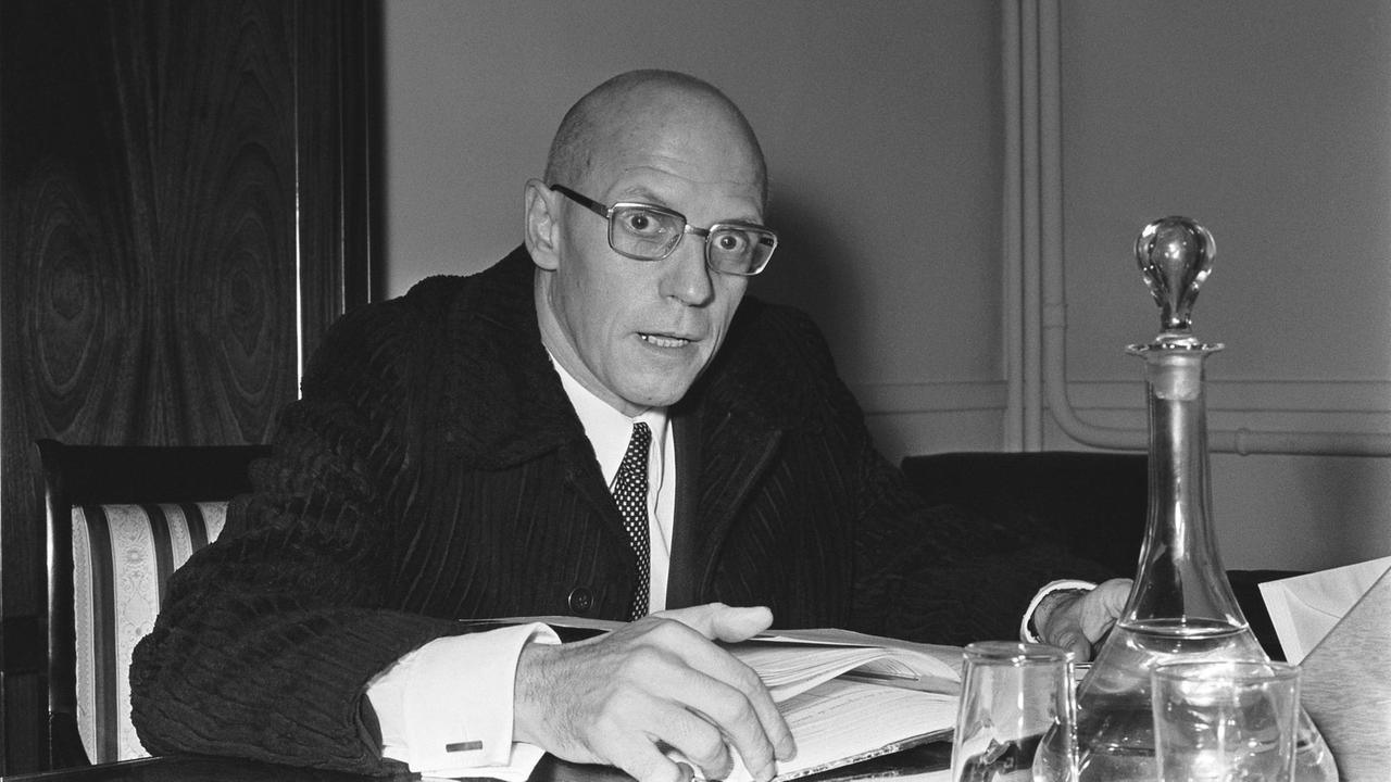 Schwarz-weiß-Aufnahme von Michel Foucault in seinem Arbeitszimmer im Collège de France, Paris, 1970.