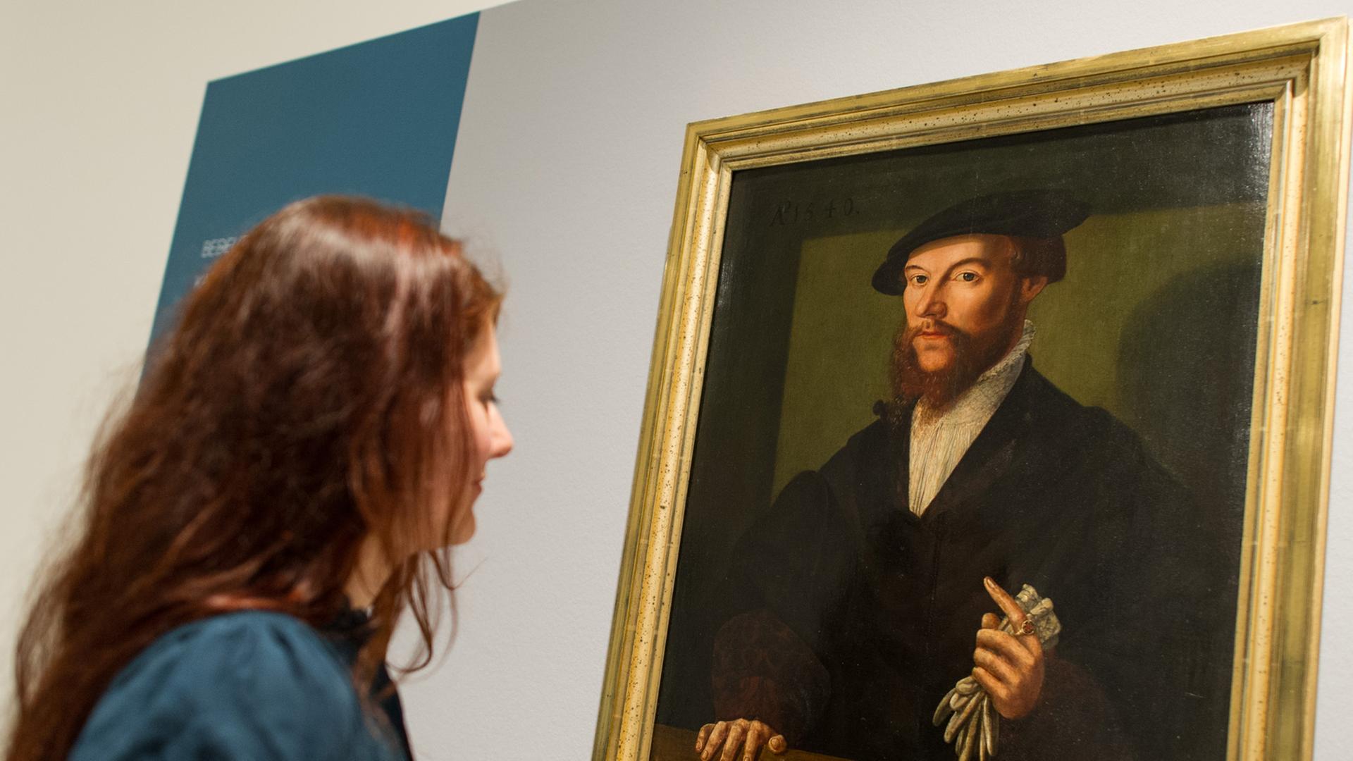 Eine Frau betrachtet am 10.05.2013 in Heidelberg (Baden-Württemberg) im Kurpfälzischen Museum in der Ausstellung "Macht des Glaubens" ein Ölgemälde, das den Reformator Johannes Calvin zeigt.