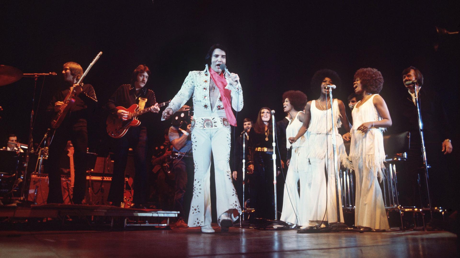 Begleitet von einer Band und Hintergrund-Sängerinnen tritt das US-amerikanische Rock-Idol Elvis Presley in Las Vegas/Nevada auf. Undatierte Aufnahme.