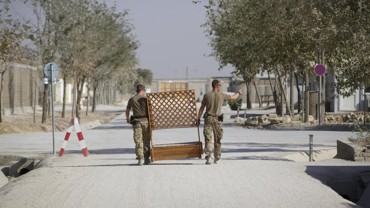 Soldaten der Bundeswehr in Kundus tragen einen Holzzaun.