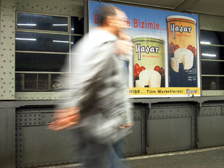 Ein Mann rennt an einer türkischen Reklame am Kottbusser Tor in Kreuzberg (Berlin) vorbei.