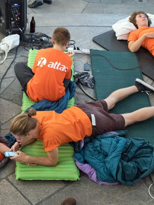 Attac-Aktivisten machen es sich auf ihren Schlafsäcken in der Paulskirche gemütlich. Zuvor hatten sie als symbolischer Protest den Gedenkort besetzt und wollen dort über Nacht bleiben.