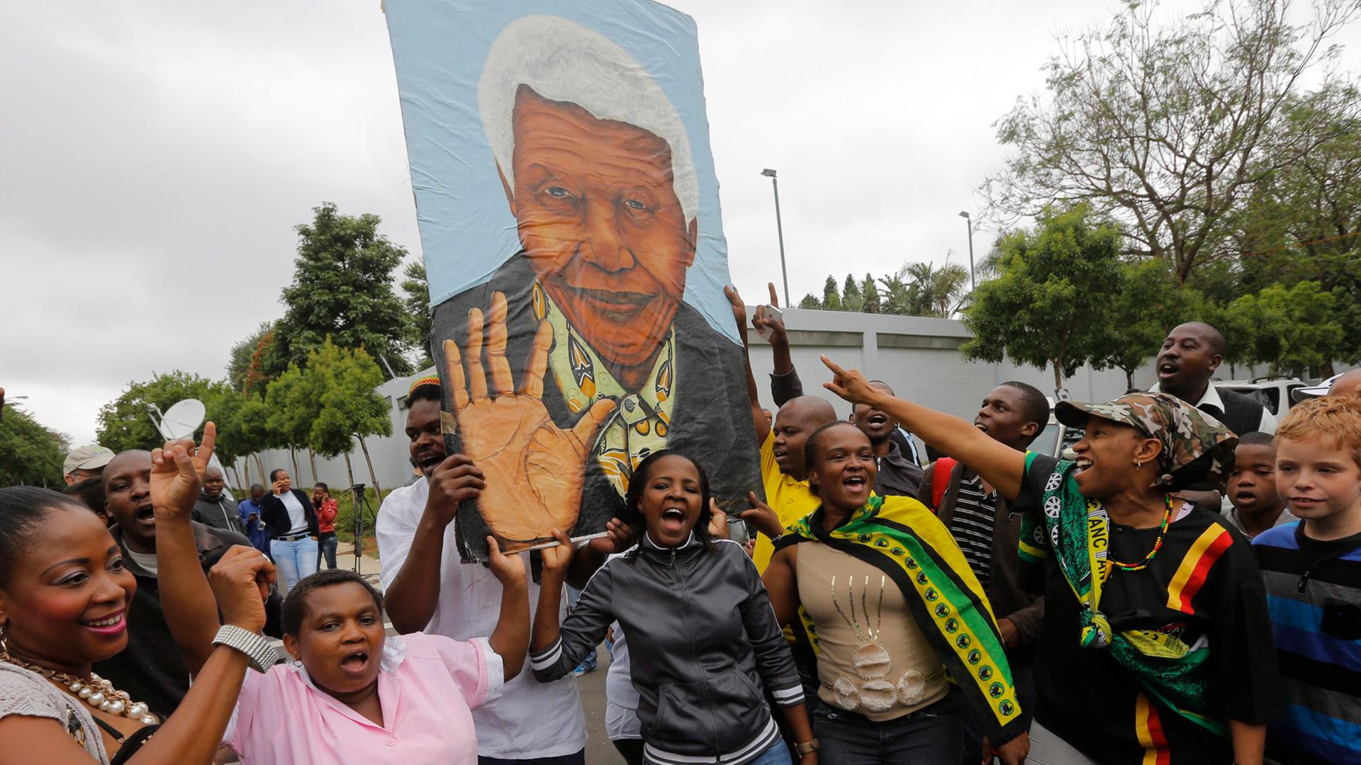 Trauernde in Johannesburg mit einem Bild Mandelas