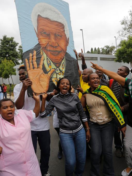 Trauernde in Johannesburg mit einem Bild Mandelas