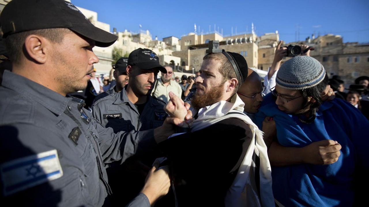 Ein ultra-orthodoxer jüdischer Mann streitet mit einem Polizeibeamten, während eines von der Organisation "Women of the Wall" organisierten Gebetes, das nicht abgebildet ist.
