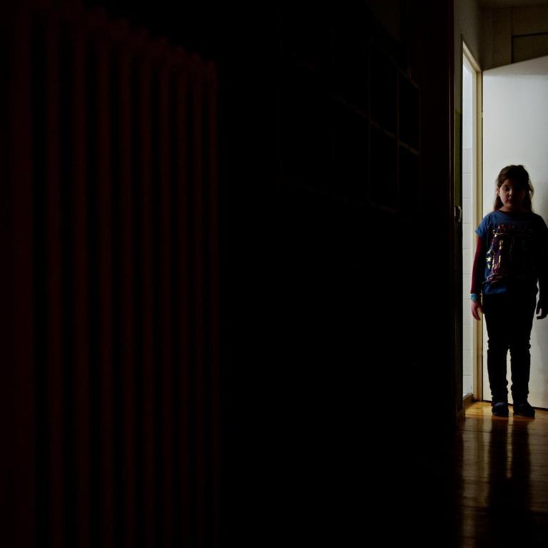 Ein junges Mädchen steht am 24.01.2014 in Berlin am Ende eines dunklen Flures.