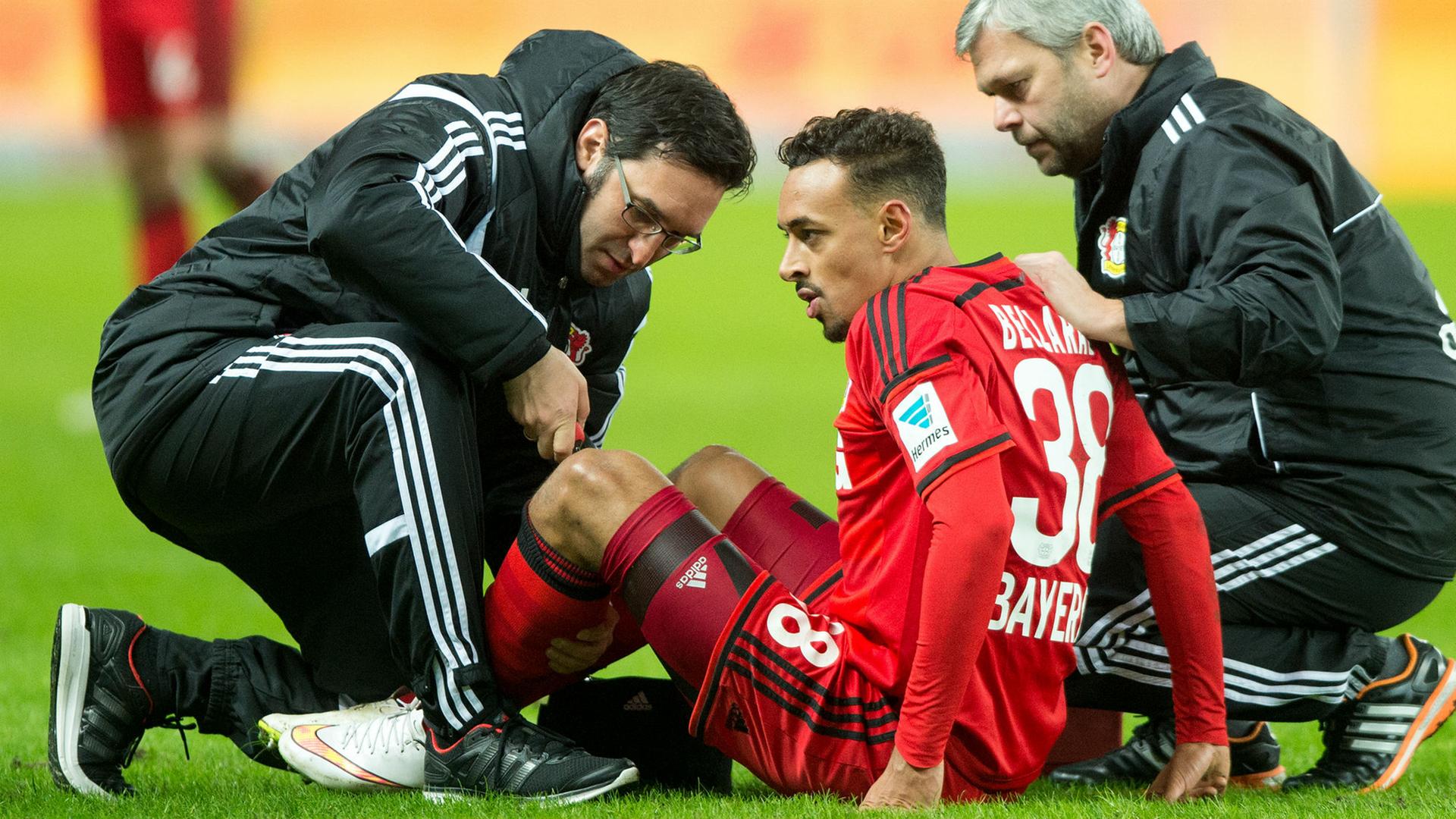 Karim Bellarabi von Leverkusen wird von Mannschaftsarzt Burak Yildirim (l) und Physiotherapeut Sven Elsinger (r) behandelt.