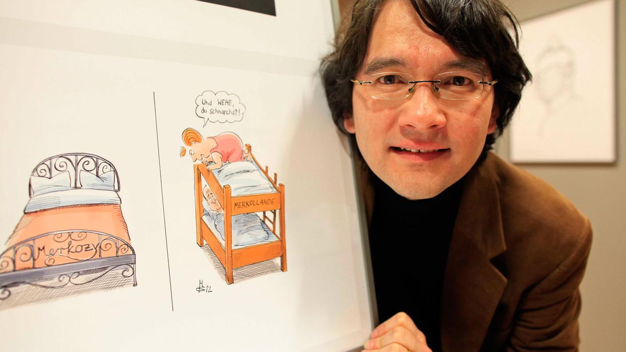 Der deutsche Karikaturist Heiko Sakurai zeigt sein Werk zum "Europäischen Paar" Deutschland und Frankreich bei einer Ausstellungseröffnung.