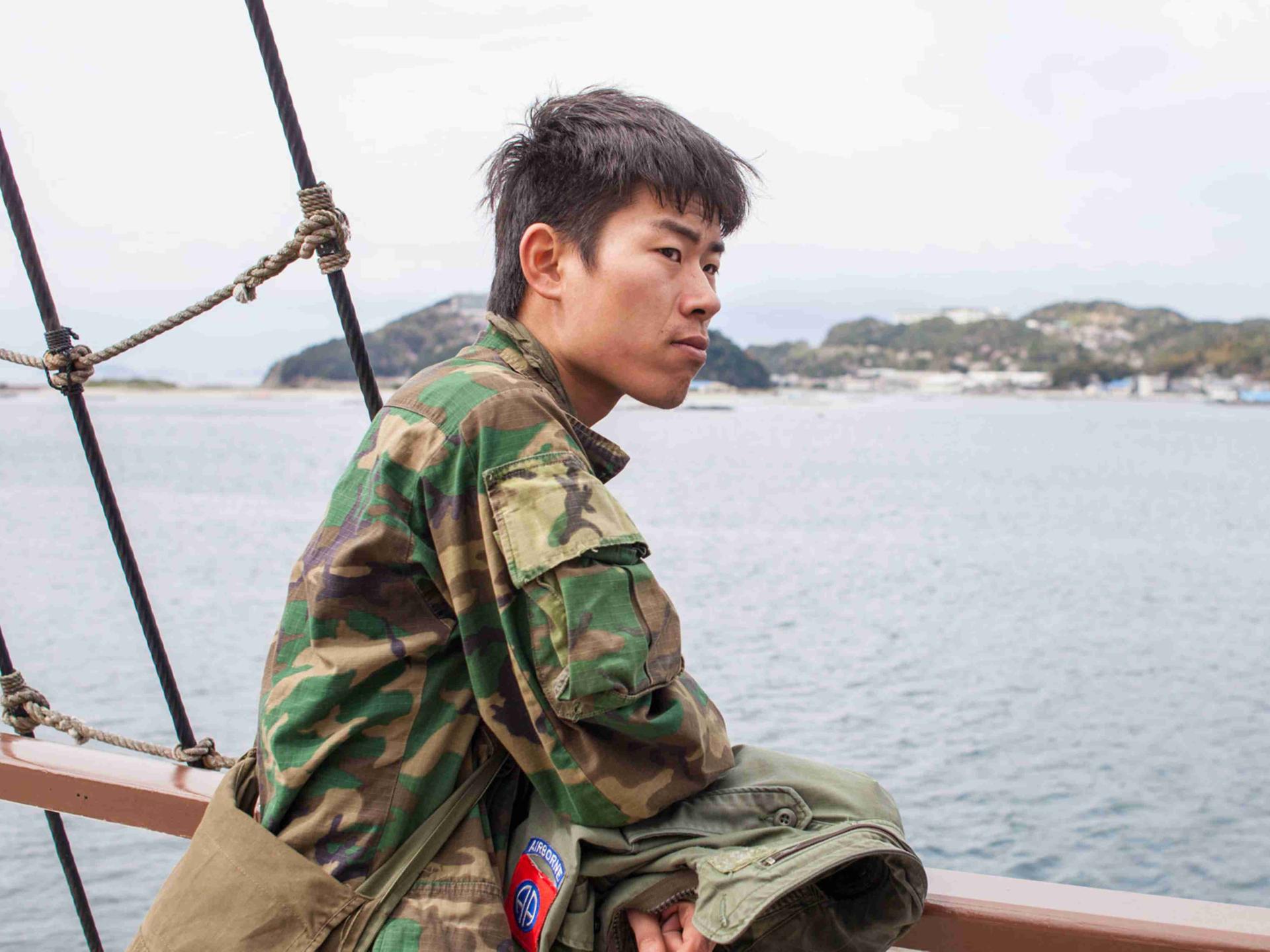 Kei im Militärstil-Camouflage-Hemd auf einem Schiff vor der japanischen Insel Awaji