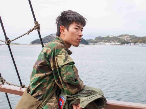 Kei im Militärstil-Camouflage-Hemd auf einem Schiff vor der japanischen Insel Awaji